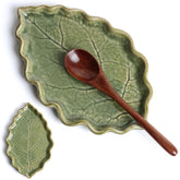 Anoonse ceramic spoon rest with green leaf design on countertop.