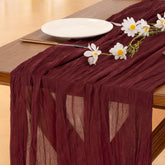 Socomi burgundy cheesecloth table runner on a long table for elegant ambiance