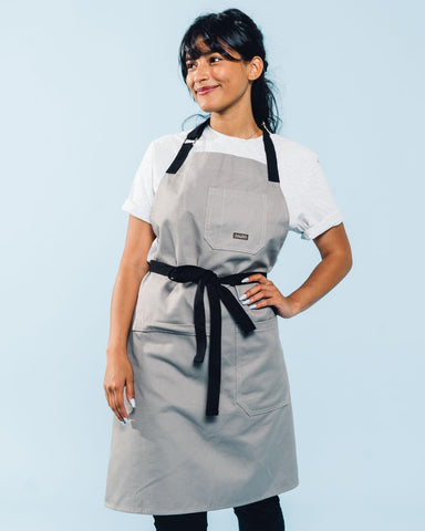 Caldo grey apron showing large pocket on the side for tools during cooking
