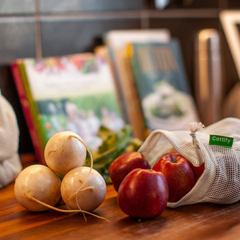 Farmers market scene with Cottify bags for reusable produce shopping.