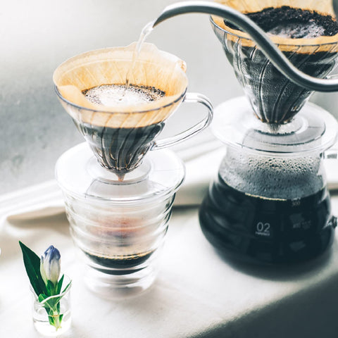 Hario V60 clear dripper next to a cup ideal for travel-friendly coffee rituals