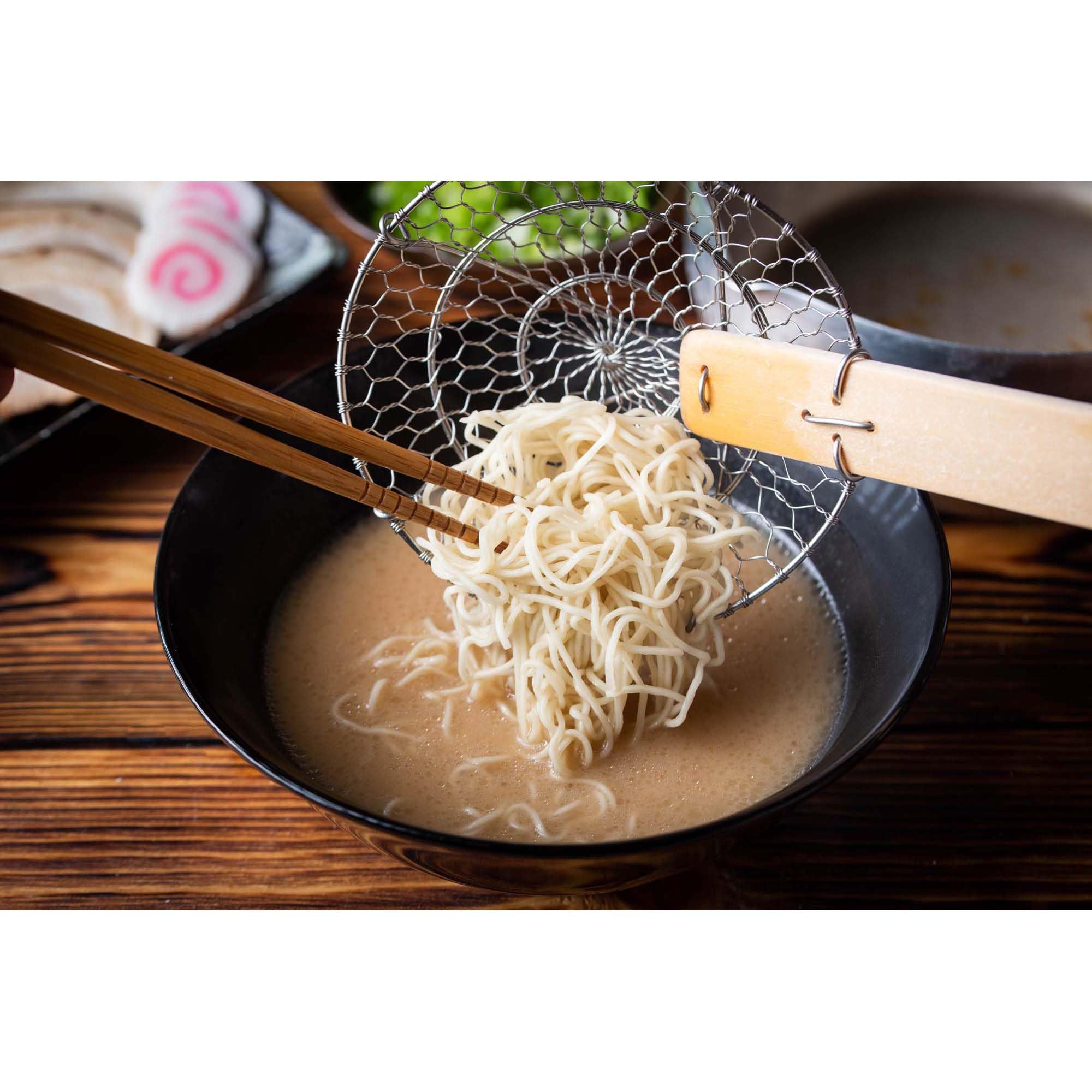 Helen's Asian Kitchen Spider Strainer hangs on a rack for easy storage in the kitchen.