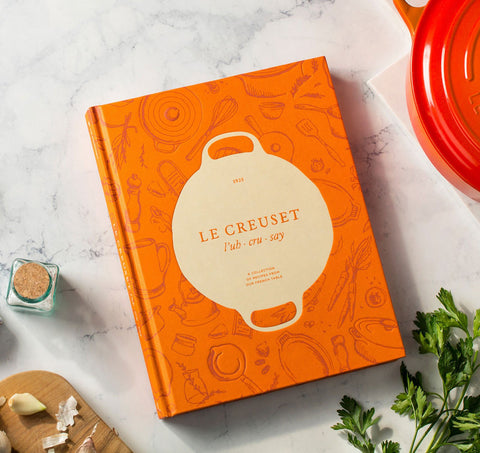 Le Creuset Cookbook open page shows recipes and techniques for guided cooking.