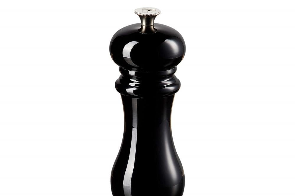 Le Creuset pepper mill on a dining table with peppers ready for seasoning.