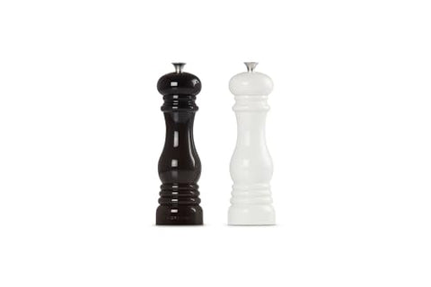 Le Creuset salt and pepper mills set on a dining table.