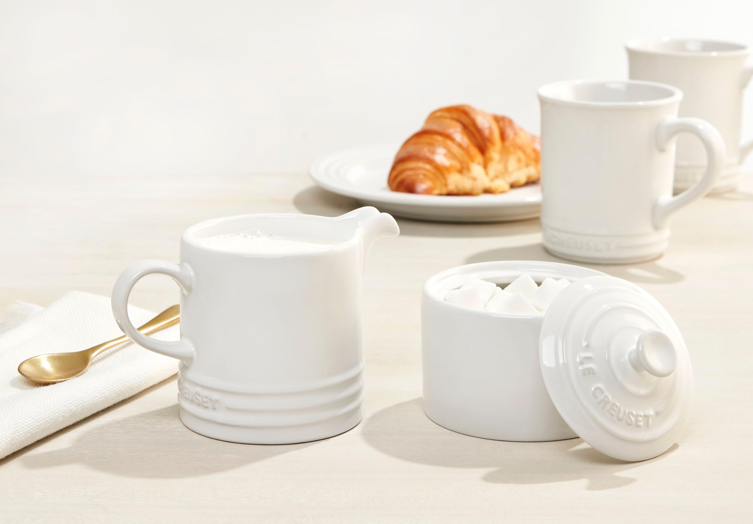 Le Creuset stoneware mugs 4 white complete set arranged for display.