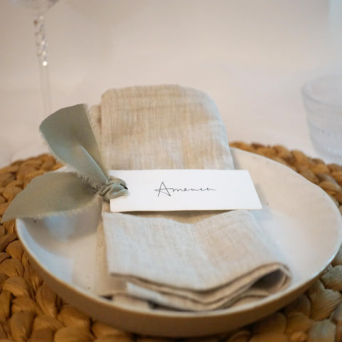 Maegmew dusty green place cards with ribbon help personalize dinner seating.