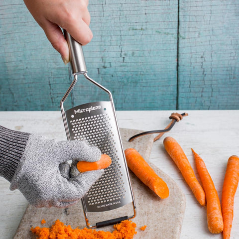 Microplane grater in use over cheese, demonstrating quick, smooth grating.