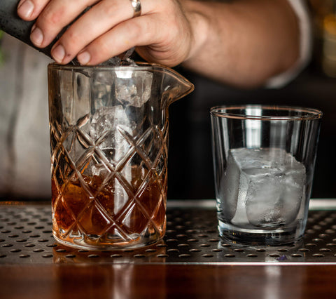 Mixologists mixing glass with two-drink capacity for efficient batching.