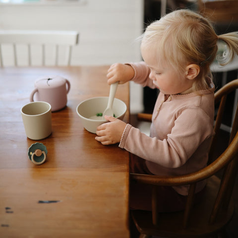 Mushie ivory cups stacked neatly for compact storage in a cabinet.