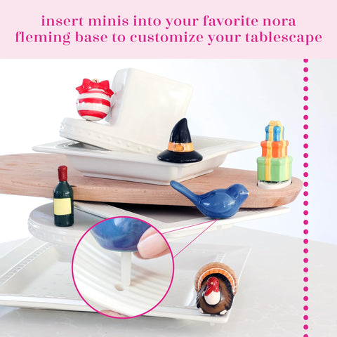 Vibrant Nora Fleming champagne mini adds festive charm to any tablescape.