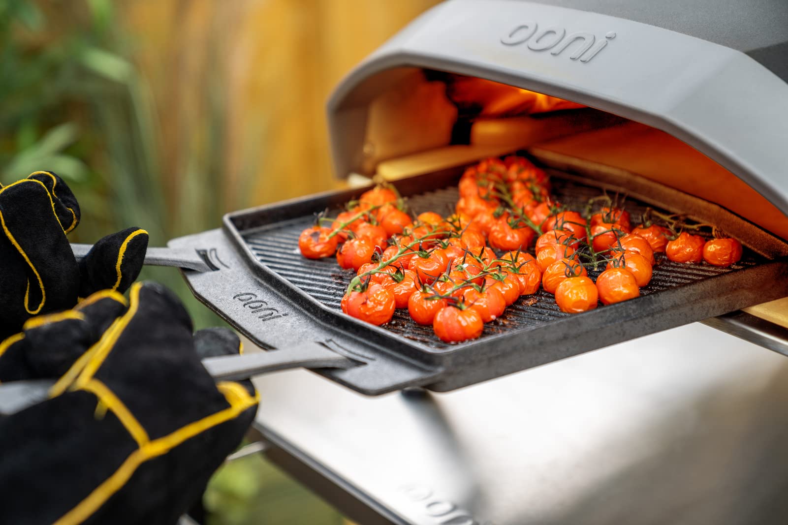 Ooni cast-iron plate with removable handle for safe oven transfer.