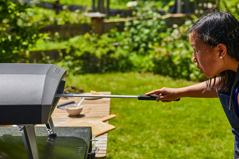 Ooni pizza turning peel slides easily under pizzas for quick transfer.