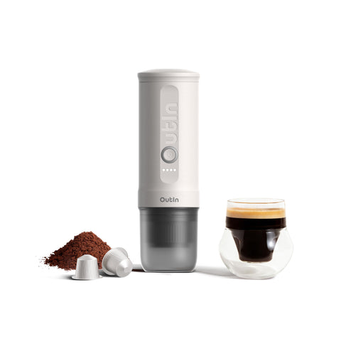 OutIn Nano portable espresso machine on camping table delivering rich crema on the go.