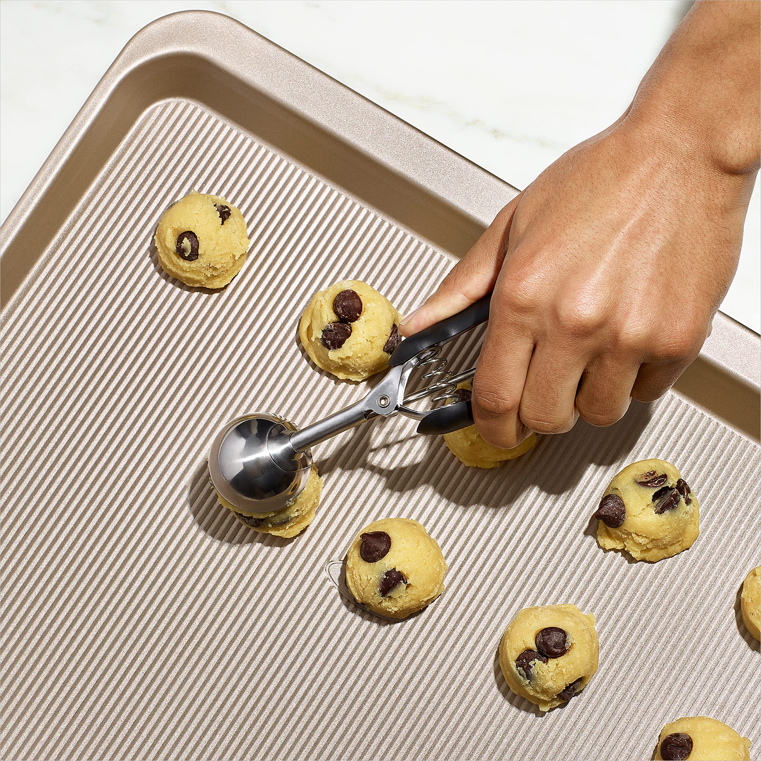 OXO Good Grips cookie sheet edge grip close-up emphasizes secure handling.