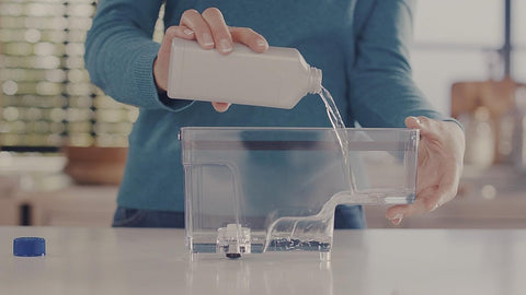 Close-up of Philips CA6700/22 descaler bottle with clear liquid.