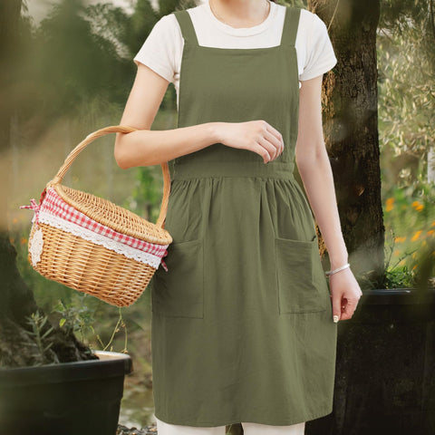 Pinknoke olive green apron worn with wearable shoulder straps for extended kitchen comfort.