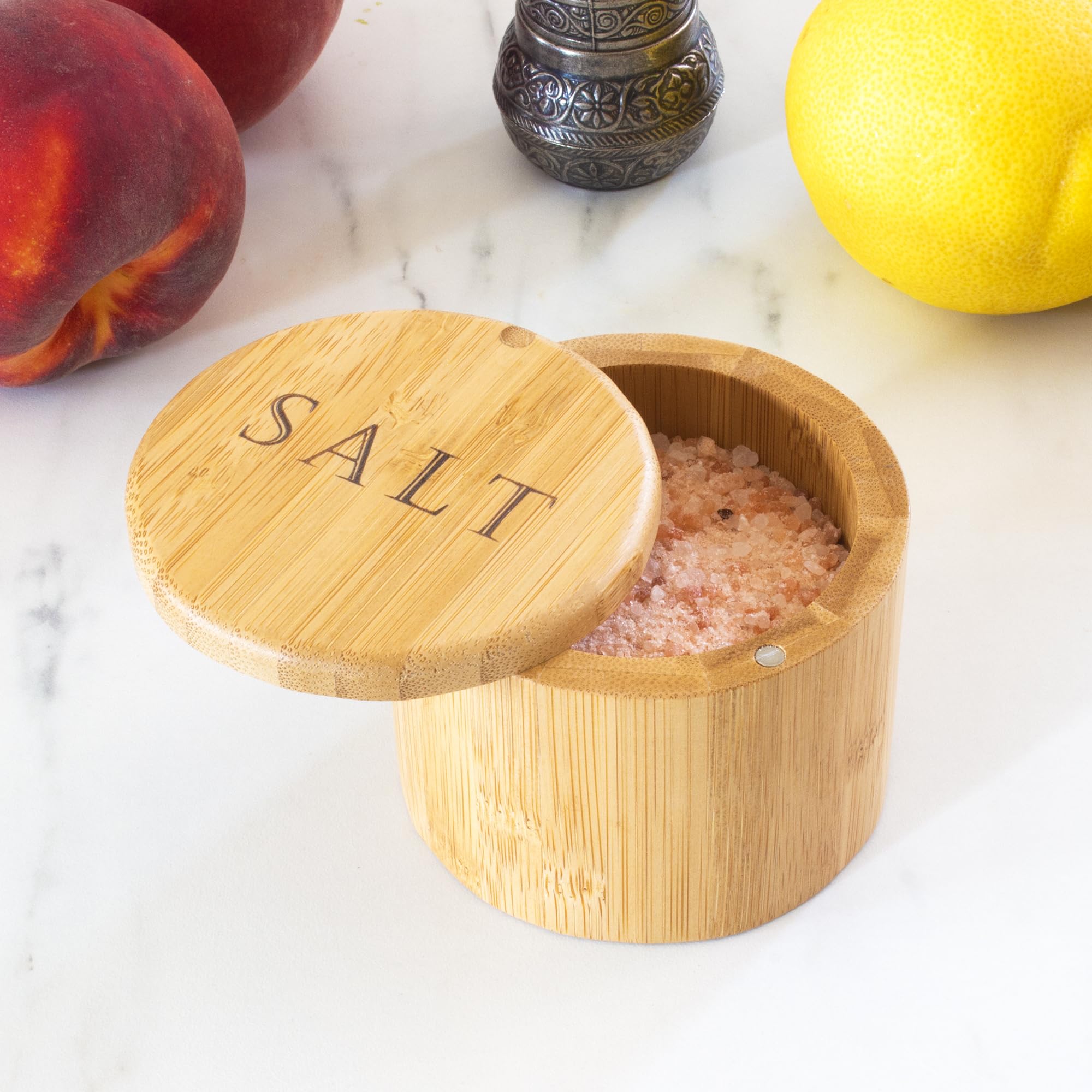 Totally Bamboo salt cellar resting on a kitchen counter with herbs nearby.