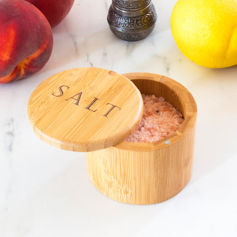 Totally Bamboo salt cellar resting on a kitchen counter with herbs nearby.