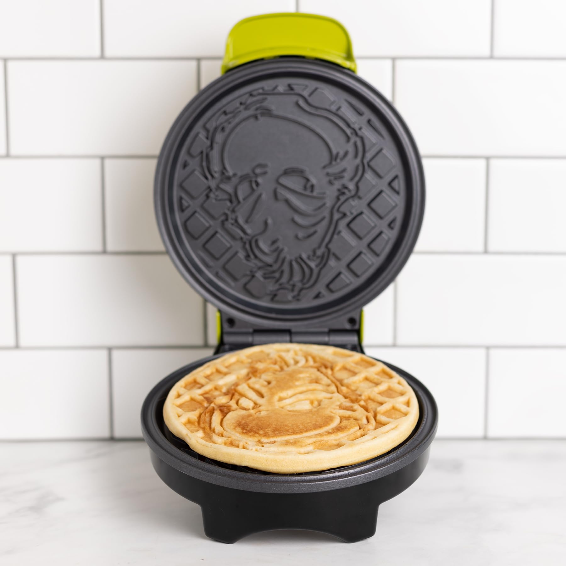 Uncanny Brands Grinch waffle maker non-stick plates for easy cleaning.