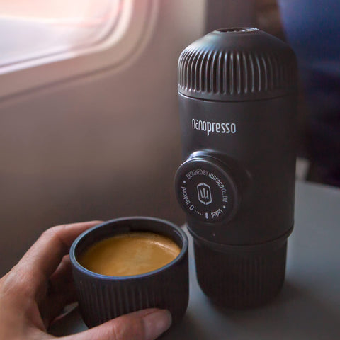 Compact Nanopresso beside a water bottle, ideal for camping and travel.